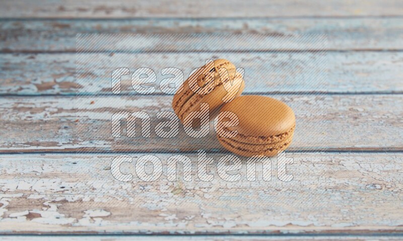 45º Shot of two Brown Maple Taffy macarons on light blue wooden background