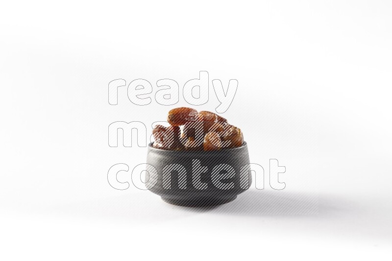 Dates in a black pottery bowl on white background