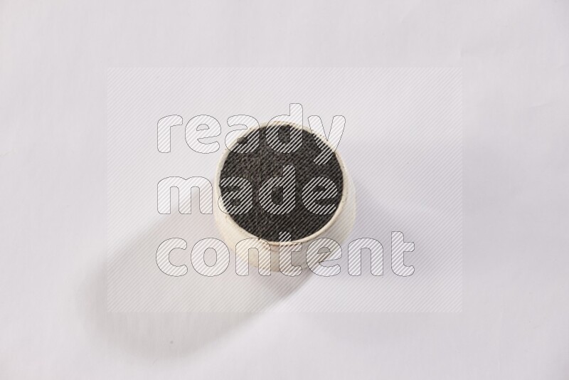 وعاء بيج فخاري ممتلئ ببذور حبة البركة علي خلفية بيضاء