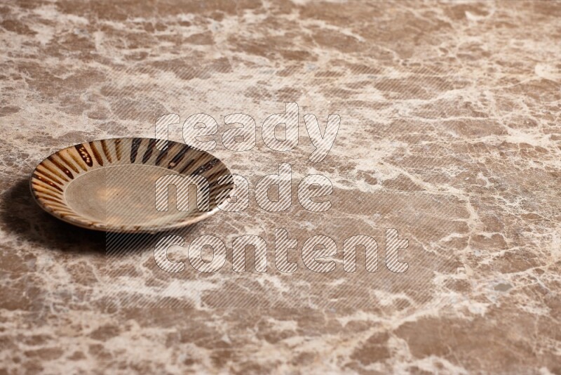 A multicolored pottery plate on beige marble background