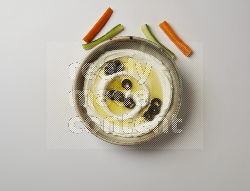 Lebnah garnished with sliced olives in a grey pottery plate on a white background