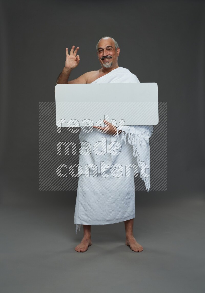 A man wearing Ehram Standing holding social media sign on gray background