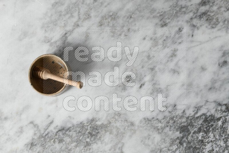 Multicolored pottery bowl with wooden honey dipper in it on grey marble background