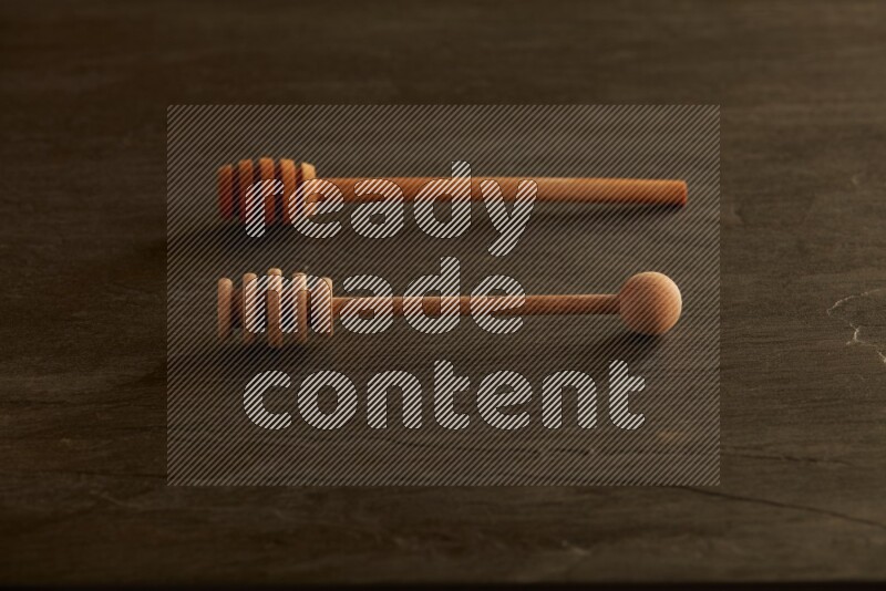 Wooden honey dipper on black slate background