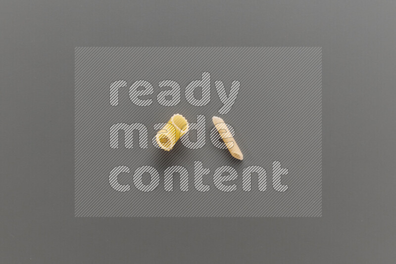 Elbow pasta with other types of pasta on grey background