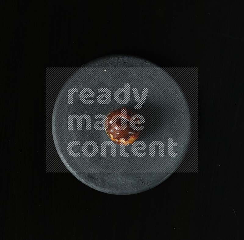 Assorted desserts in a black pottery plate on black background