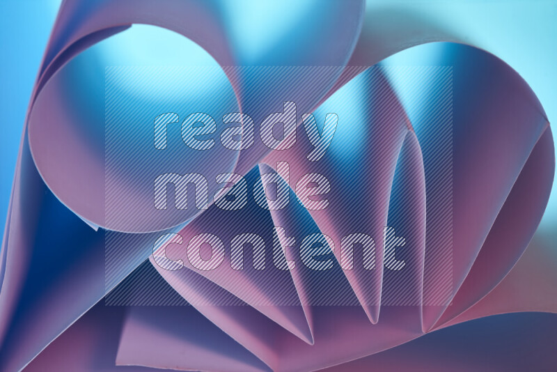 An artistic display of paper folds creating a harmonious blend of geometric shapes, highlighted by soft lighting in blue and pink tones