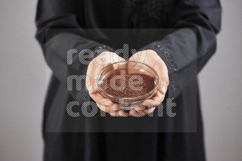 Woman in abaya holding different kinds of spices in different positions