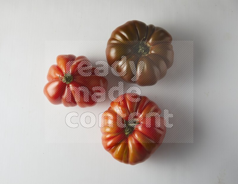 three heirloom tomatoes topview on a white background