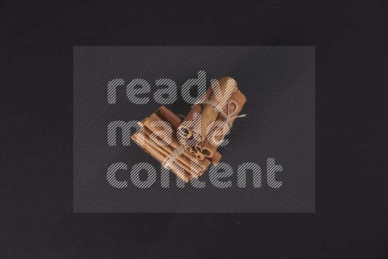Two bounded stacks of cinnamon sticks on black background