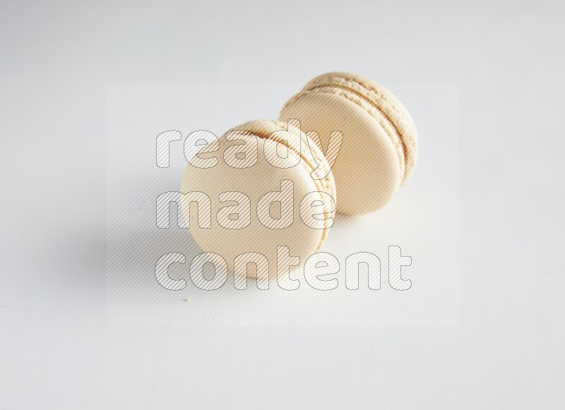 45º Shot of two White Caramel fleur de sel macarons on white background