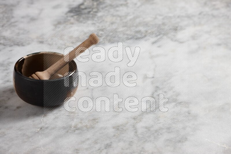 Multicolored pottery bowl with wooden honey dipper in it on grey marble background