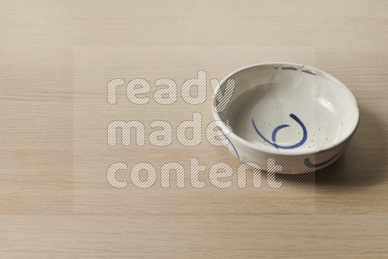 A multicolored pottery bowl on light wooden background