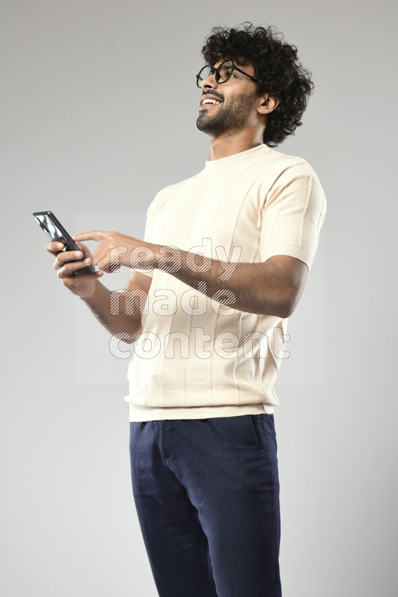 A man wearing casual standing and browsing on the phone on white background