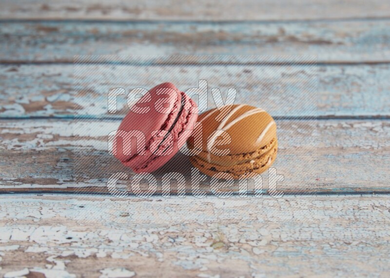 45º Shot of of two assorted Brown Irish Cream, and Pink Raspberry macarons on light blue background