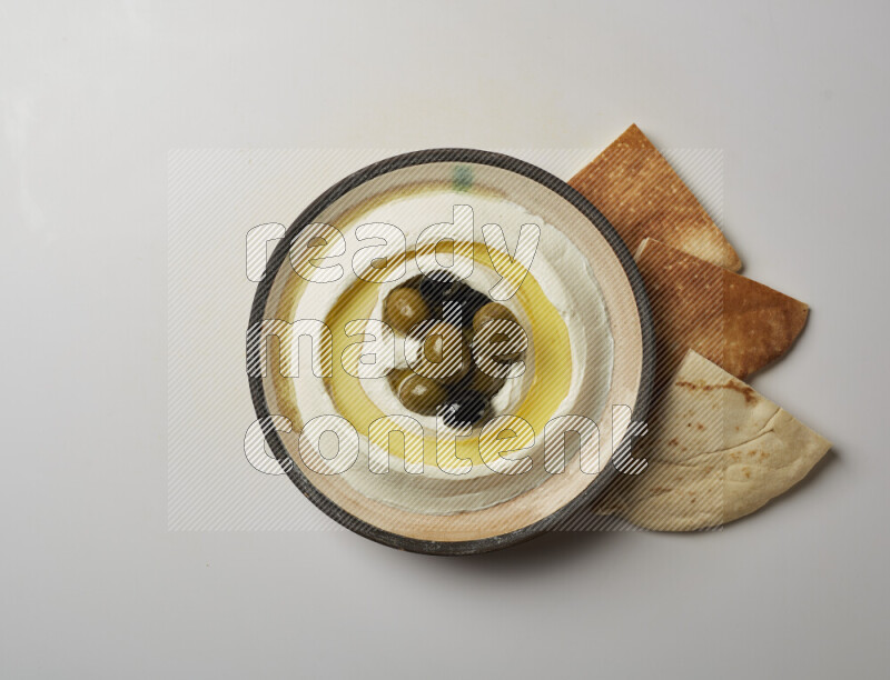 Lebnah garnished with whole black olives in a pottery plate on a white background