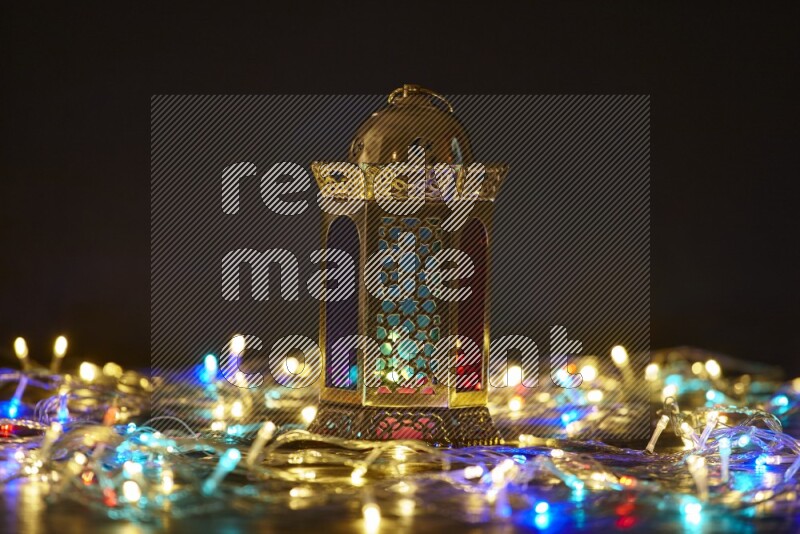 A traditional ramadan lantern surrounded by glowing fairy lights in a dark setup