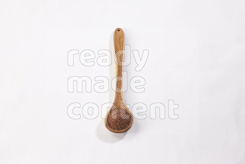 ملعقة خشبية كبيرة ممتلئة ببذور حب الرشاد علي خلفية بيضاء