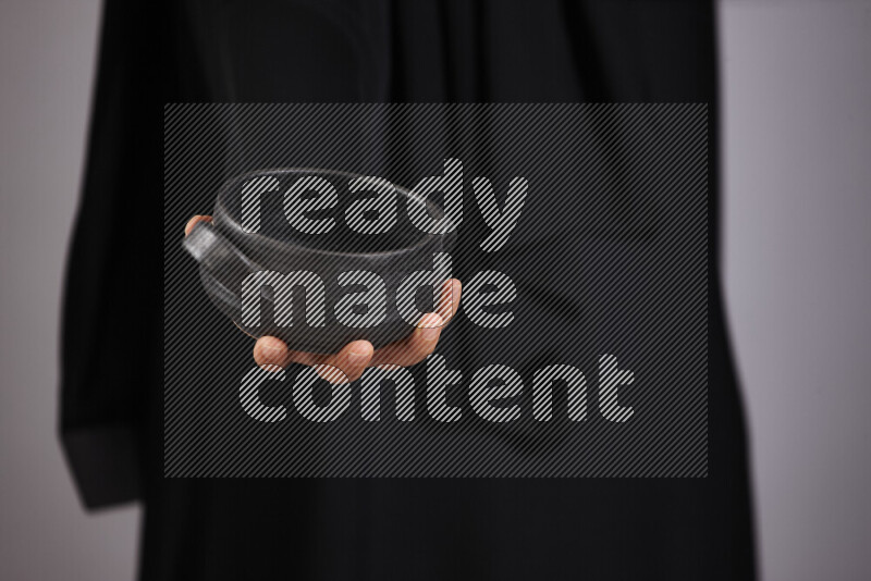 امرأة ترتدي عباءة سوداء تحمل أدوات فخارية مختلفة في أوضاع متعددة