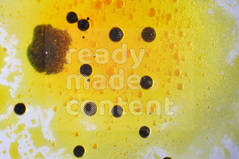 لقطات مقربة لقطرات ألوان مائية صفراء وسوداء على سطح الزيت على خلفية بيضاء