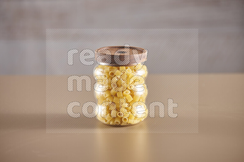 Raw pasta in glass jars on beige background