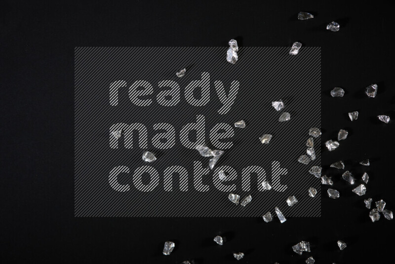 Silver shimmering fragments of glass scattered on a black background