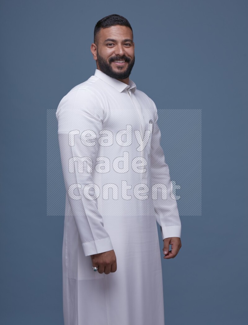 A man Posing in Blue Background wearing a Saudi Thob