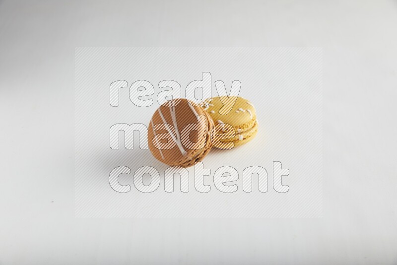 45º Shot of of two assorted Brown Irish Cream, and Yellow Piña Colada macarons on white background
