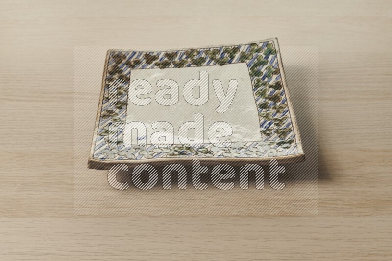 A decorative pottery plate on light wooden background