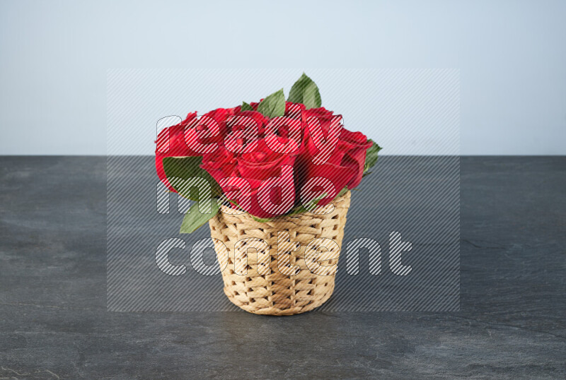 Vibrant red roses in a wicker basket on black marble background