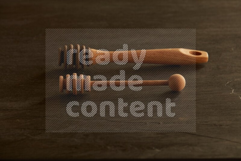 Wooden honey dipper on black slate background