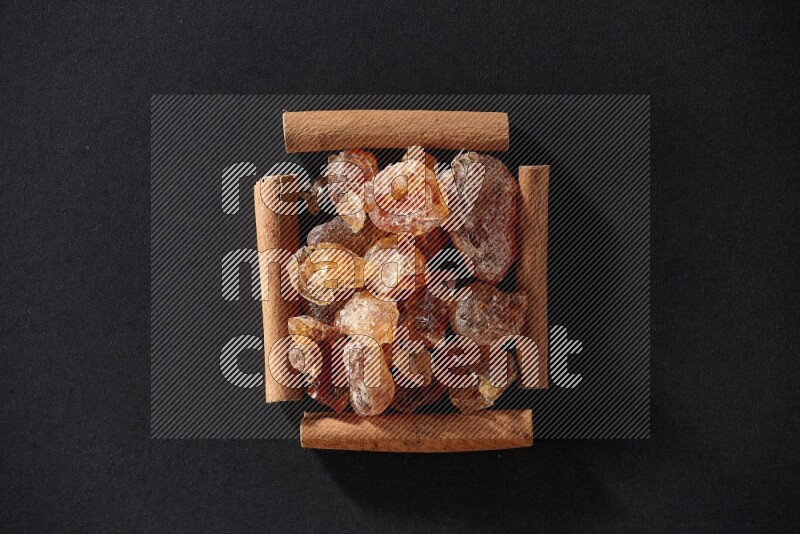 A single square of cinnamon sticks full of Arabic gum on black flooring