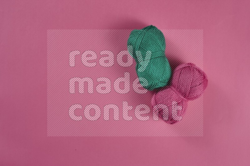 A green and pink collection of sewing and tailoring tools arranged on a pink background