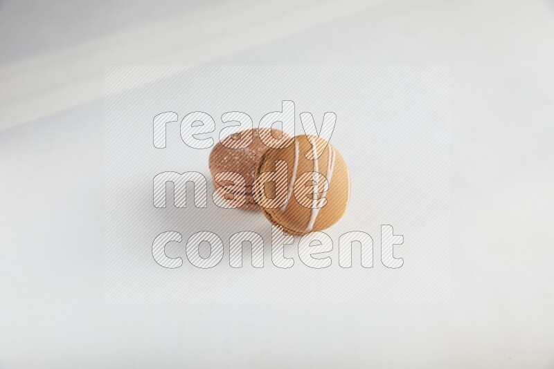 45º Shot of of two assorted Brown Irish Cream, and Brown Hazelnuts macarons on white background