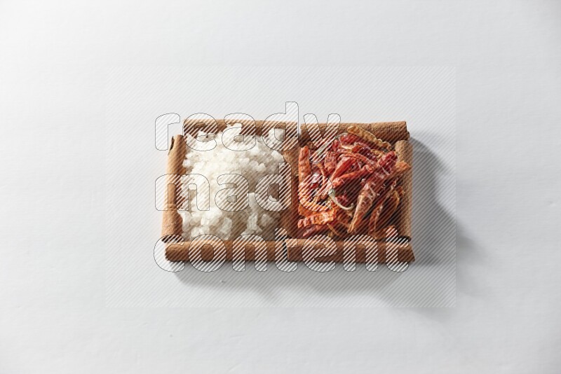 2 squares of cinnamon sticks full of dried red chilis and white salt on white flooring