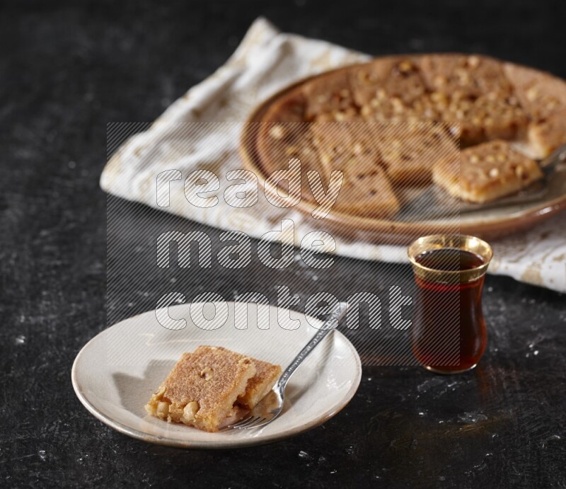 Basbousa with tea in a dark setup