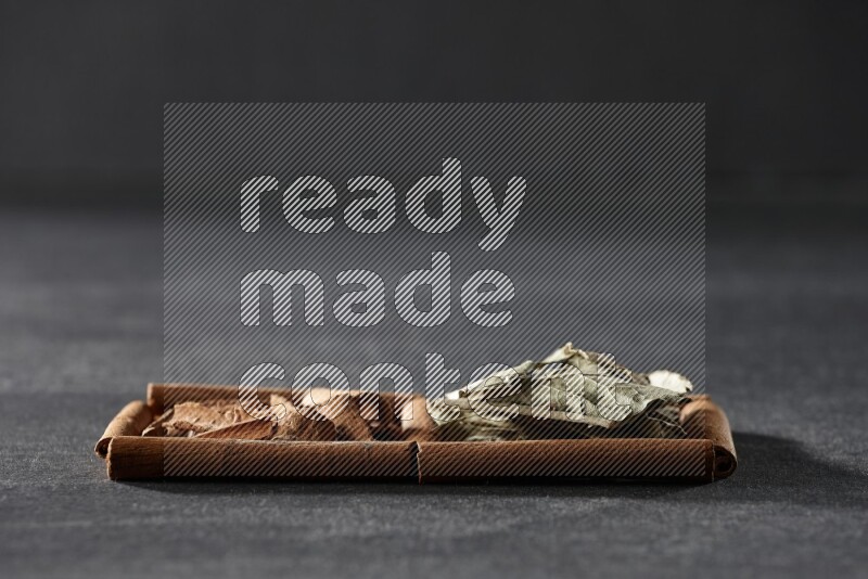 2 squares of cinnamon sticks full of cinnamon and bay laurel leaves on black flooring