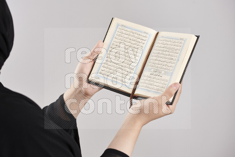 امرأة تحمل بيديها مصحف القرآن في أوضاع متعددة