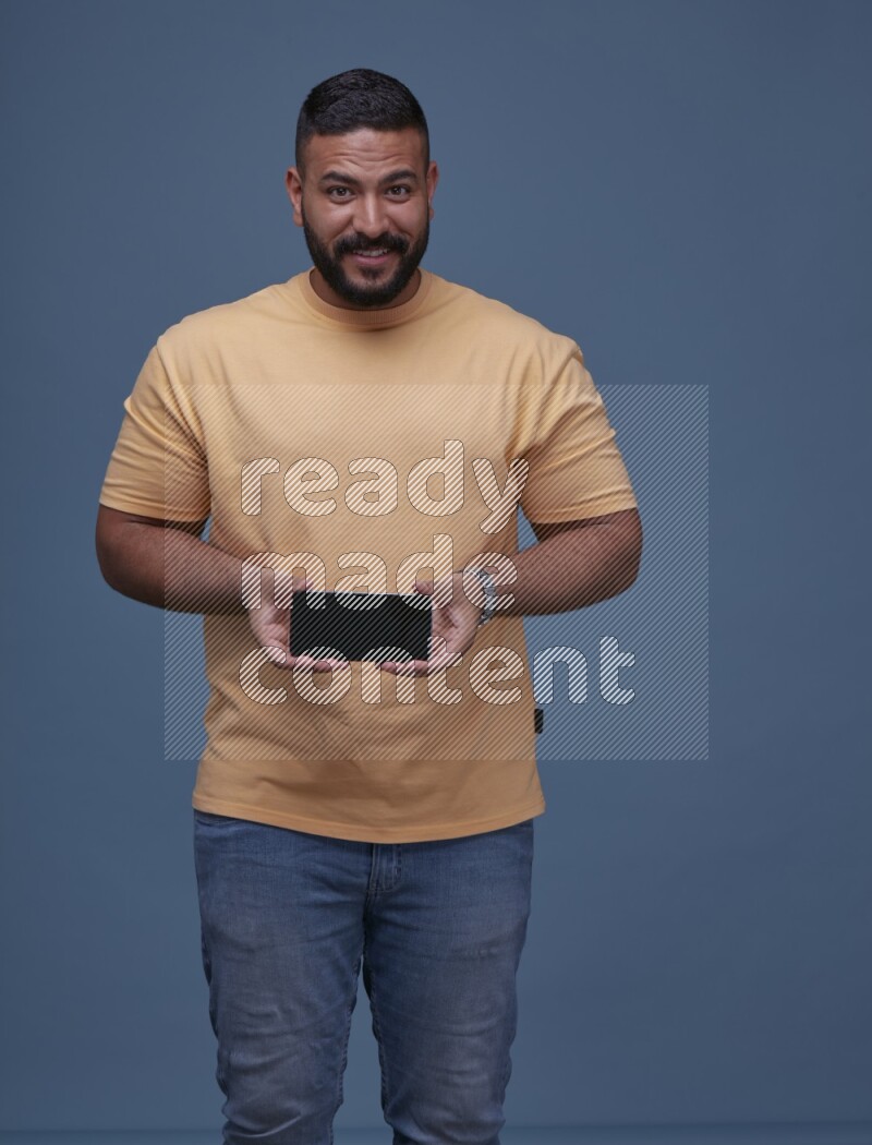 A man Showing His Smart Phone on Blue Background wearing Orange T-shirt