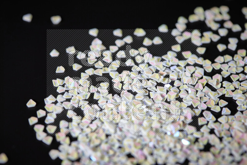 قطع صغيرة بلاستيكية ملونة للزينة متناثرة على خلفية سوداء