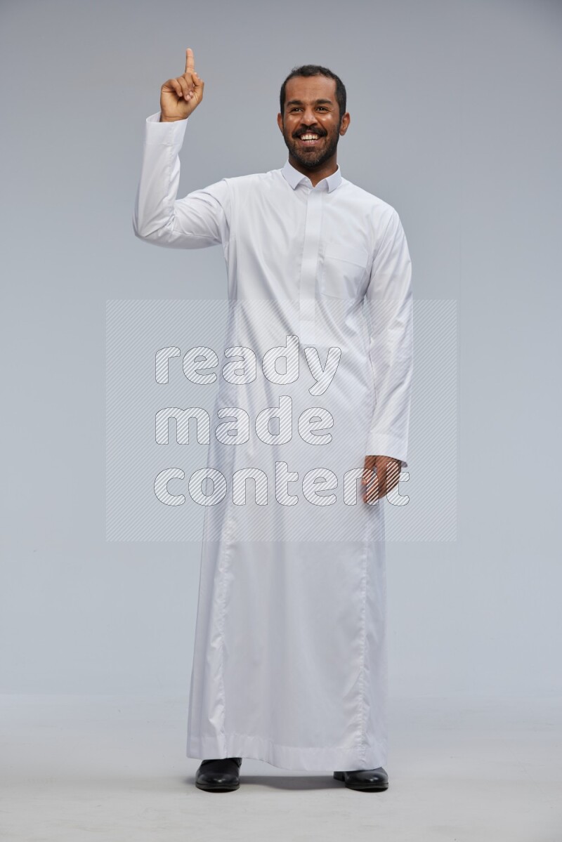 Saudi man Wearing Thob standing interacting with the camera on Gray background