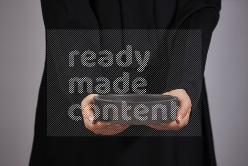 امرأة ترتدي عباءة سوداء تحمل أدوات فخارية مختلفة في أوضاع متعددة