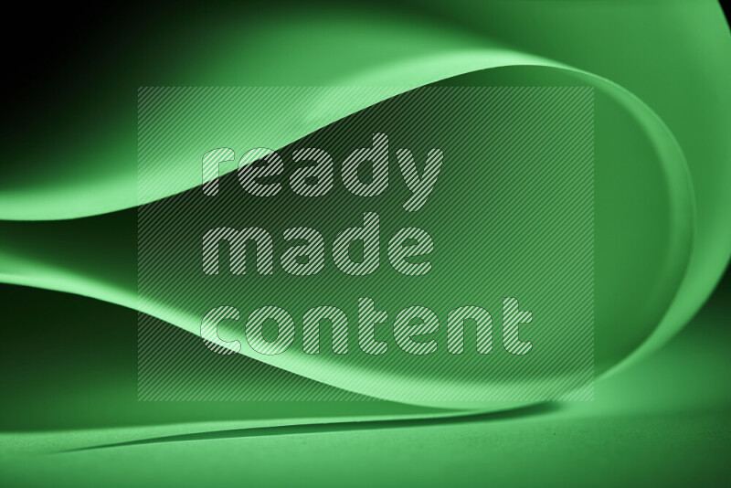 An abstract art piece displaying smooth curves in green gradients created by colored light