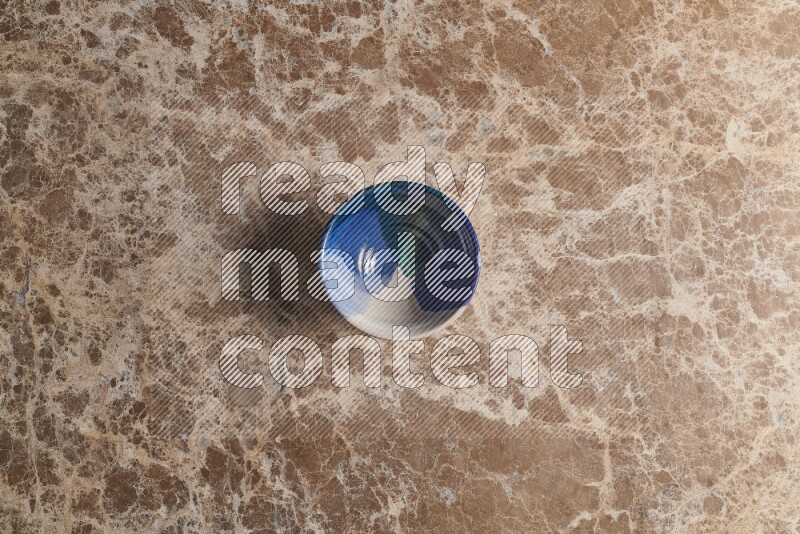 A multicolored pottery bowl on beige marble background