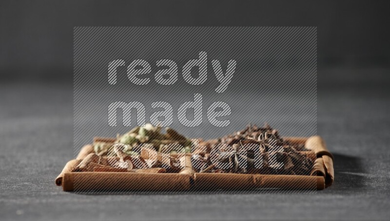 4 squares of cinnamon sticks full of cinnamon, cardamom, cloves and star anise on black flooring