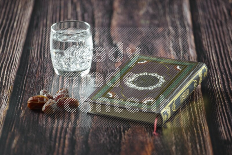 Quran with dates, prayer beads and different drinks all placed on wooden background