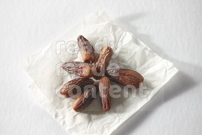 Dried dates on a crumpled piece of paper on a white background in different angles