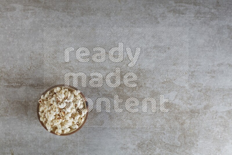 popcorn in wooden bowl on a grey textured countertop