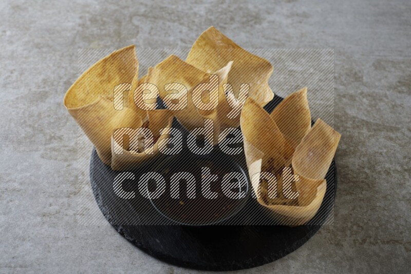 wonton cups with soy sauce ramkin on circle slate on grey textured counter top