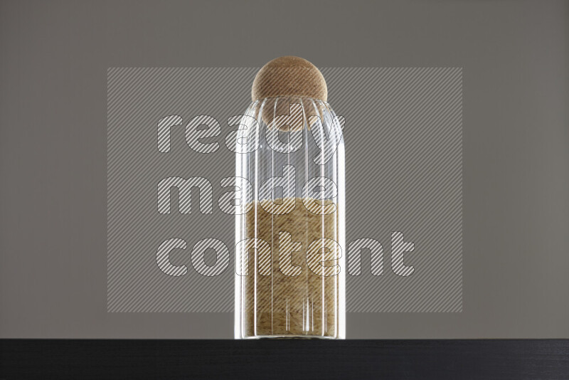 Basmati golden rice in a glass jar on black background